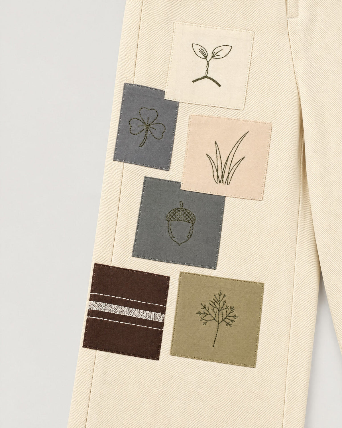 The Sampler Jeans in Ecru — hand-embroidered sampler patches