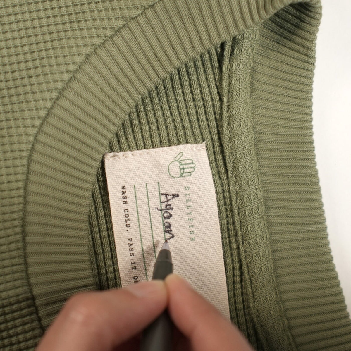 A tape ruled with three lines inside every collar — one for each child who wears the garment.